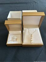 Both pendant necklace and ring presented in gold-tone jewelry boxes