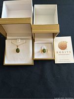 Pendant and ring displayed in gold presentation boxes alongside Korite certificate