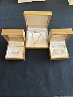 Top-down view of ring, pendant on chain, and earrings displayed in individual jewelry boxes