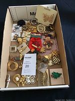 Photo showing the full collection of assorted vintage brooches in various shapes including butterflies, birds, Christmas trees, insects, hearts, and floral motifs laid inside a cardboard box.