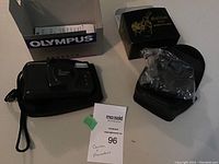 Olympus Zoom XB 70 camera with carrying case next to Galileo binoculars in their protective case and box.