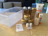 Full view of all items in skincare set including clear plastic container and creams with ornate gold lids.