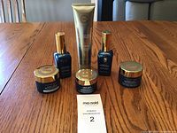 Six Elizabeth Grant skincare products arranged on a wooden table, including jars, bottles, and a tube.