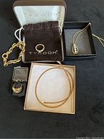 Photo showing entire jewelry set including two rings in Tycoon boxes, chain link bracelet, teardrop pendant on chain, and mesh choker necklace.