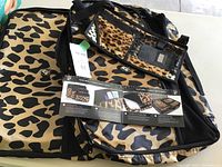 Eight Heys luggage packing cubes in black and tan leopard print showing front and top views with mesh panels and handles, plus a car visor holder shown on top with clear pockets and zipper.