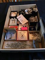 Overview photo showing boxed and loose silver-toned jewelry including necklaces, bracelets, rings, and earrings, some with stones.