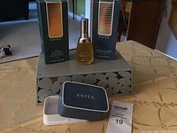 Lot overview showing three Estée Lauder Eau de Parfum bottles (two boxed, one loose), grey branded container, and soap dish on patterned tablecloth.