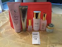 Full view of all skincare and bath products arranged in a line on a table with a red container in the background.