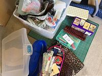 Full view of large tote filled with assorted fabric pieces, plastic containers, cutting mat, and carry bags