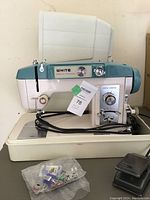 Full side view of the sewing machine on its base with foot pedal and accessory bag visible.