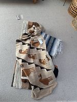 Photo of multiple woven blankets and throws laid on carpet showing various patterns and colors.