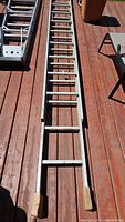 Full view of 18ft aluminum extension ladder on wooden deck, showing length and overall condition.