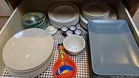 Overview of dishware including stacked white plates, egg cups, ceramic spoon rest, and serving platters.