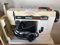 Full side view of PFAFF Hobbymatic 807 sewing machine showing brand name, stitch selection panel, control dial and attached foot pedal with power cord.