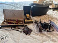 Overview of lot showing Pulsar watch in box, Fitbit Versa 2 smartwatch and charger, Timex watch, vintage razor, box with cufflinks, chain, and tie clips.