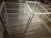 Photo showing two white wire drawer storage units with multiple wire basket drawers, rectangular shape and metal frames.