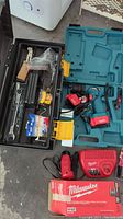 Makita cordless drill in case, battery charger, and black toolbox with various tools