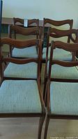 Six wooden dining chairs grouped together, showing overall style, wood finish, and upholstery.