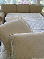 Beige Norwalk Furniture hide-a-bed sofa with cushions removed, showing quilted mattress inside.