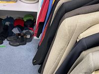 Close-up of several men's suits hanging on a rack, showing fabrics and colors.