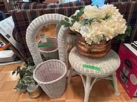 Photo of white wicker stool, basket, mirror frames, copper pot with faux flowers, and greenery