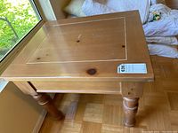 Top and corner view showing the wood grain, knots, and rectangular panel design on the top surface of the side table.