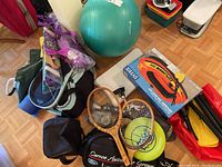 Overview photo showing exercise ball, tennis rackets, multiple bags, and the boxed inflatable boat set with paddles.