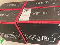 Four closed black and red boxes labeled 'Riedel Vinum' containing eight Riedel wine glasses in original packaging.