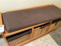 Top perspective showing wood frame, four wicker baskets in drawers, and brown cushion on top