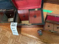 Large wooden box opened showing two sliding compartment drawers and a separate key on one drawer. Red felt lining inside the lid is visible.