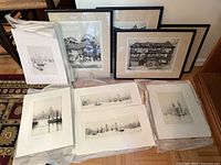 Overview of all etchings showing assortment of framed and unframed pieces with various waterfront cityscapes and boats