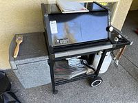 Full view of Weber grill with side shelves, wheels, propane tank and accessories