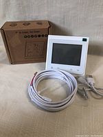 New BHT-002 Series WiFi thermostat in white shown with power cable, wired connection cable, mounting screws, and original box.