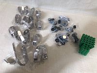Set of 16 silver metal hooks individually packaged, installation screws in small plastic bags, and group of green plastic wall anchors.