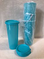 Set of four new turquoise Tupperware tumblers stacked together, with four lids beside them, all wrapped in protective plastic.