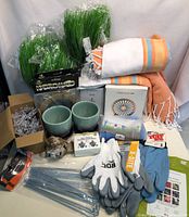 Photo showing bundles of decorative grass, garden pots, gloves, garden stakes, towels, solar light box, and seed kits.