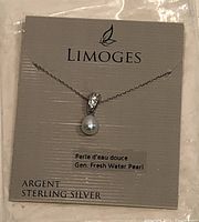 Front view of necklace displayed on card with branding and product information (Argent Sterling Silver, Genuine Fresh Water Pearl)