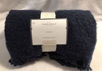 Image of folded navy blue throw with label showing Threshold brand and Studio McGee collaboration.