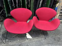 Two red Swan chairs side by side on warehouse floor