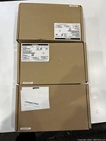 Three Lenovo ThinkPad docking stations in sealed original brown cardboard boxes with product labels on top.