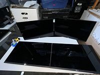 Four Dell 24-inch monitors without stands, arranged with two monitors upright and two flat on desk. Power cables included.