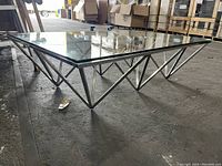 Close-up side view showing the triangular metal base and the glass top with a reflection and minor scratch visible.