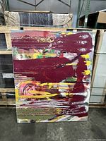 Abstract painting showing mixed brush strokes in burgundy, yellow, purple, green, and pink colors on canvas.
