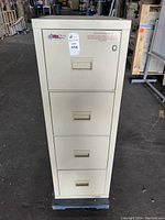 Front view of beige vertical file safe with four drawers, lock mechanism on top drawer, FireKing Turtle logo visible.