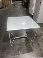 Top down angle showing glass surface with scratches and white metal frame supporting it.