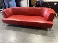 Full front view of red leather sofa showing three-seat design and chrome legs