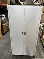 Closed front view of the white metal storage cabinet with double doors and handles.