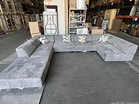 Front view of assembled grey sectional with ottomans in warehouse