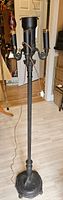 Full view of the antique iron floor lamp showing its tall stature, black iron material, and four bulb sockets.