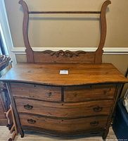 Full view of the antique oak dresser showing the curved drawer fronts, wooden knobs, and metal handles.